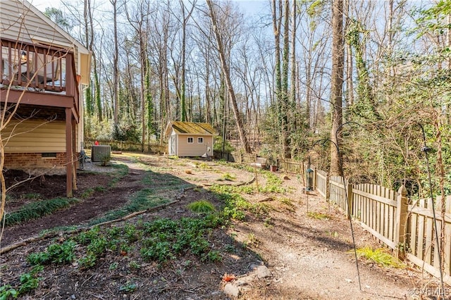 view of yard with an outbuilding, a fenced backyard, a shed, and central air condition unit