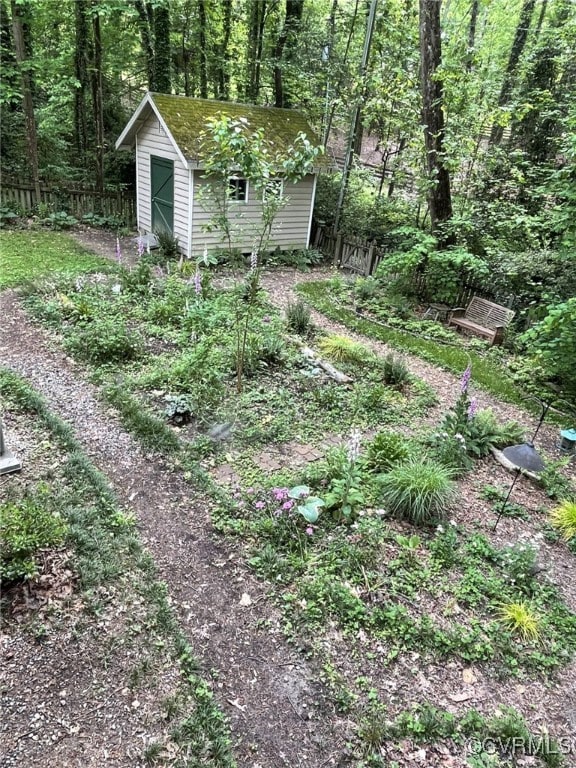 view of yard with an outbuilding, fence, a forest view, and a shed