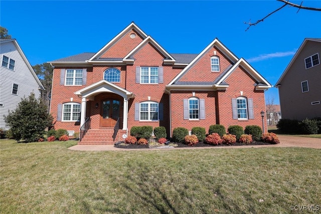 view of front facade with brick siding, a front yard, and french doors