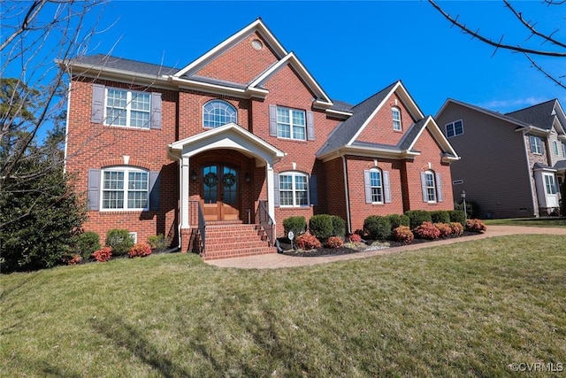 view of front of home with french doors, a front yard, and brick siding