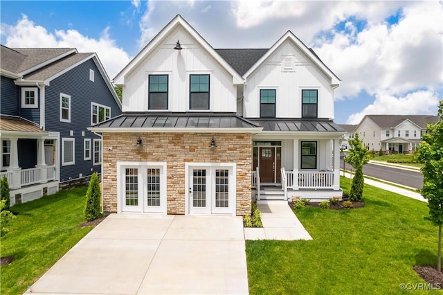 modern farmhouse featuring a standing seam roof, french doors, a front lawn, a porch, and board and batten siding