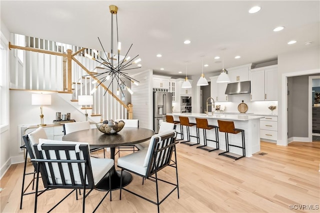 dining room with recessed lighting, an inviting chandelier, light wood-style floors, baseboards, and stairs