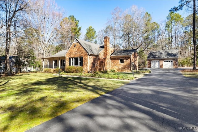 view of front of house with brick siding, a chimney, a porch, an outdoor structure, and a front lawn