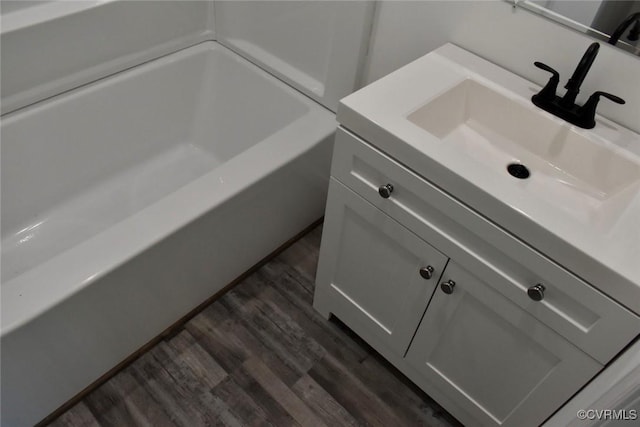 bathroom featuring a tub to relax in, wood finished floors, and vanity