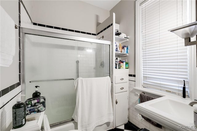 bathroom with a stall shower, a sink, and tile walls