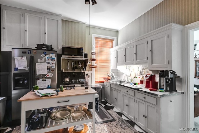 kitchen featuring light countertops, fridge with ice dispenser, stainless steel microwave, and a sink