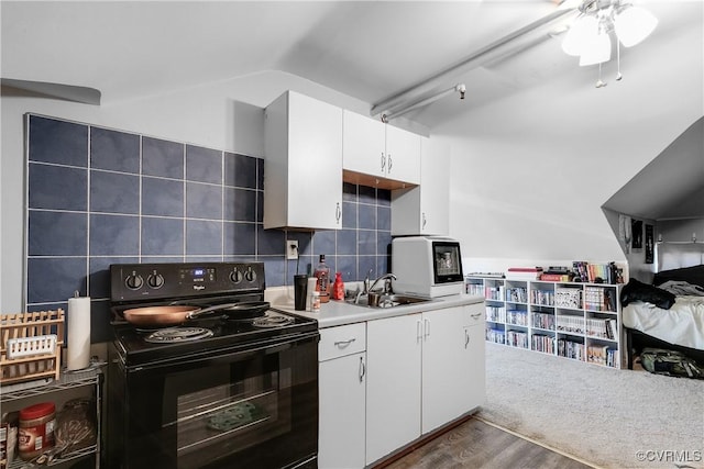 kitchen with light countertops, electric range, decorative backsplash, white cabinets, and a sink