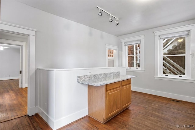 bar featuring rail lighting, baseboards, visible vents, and dark wood-type flooring