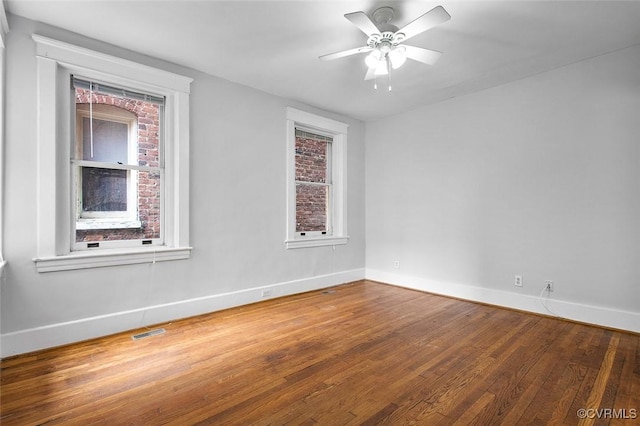 spare room with ceiling fan, wood-type flooring, visible vents, and baseboards