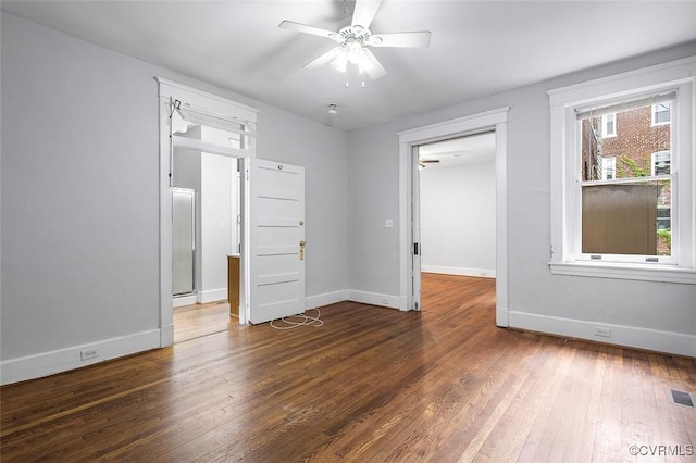 empty room with hardwood / wood-style flooring, visible vents, baseboards, and a ceiling fan