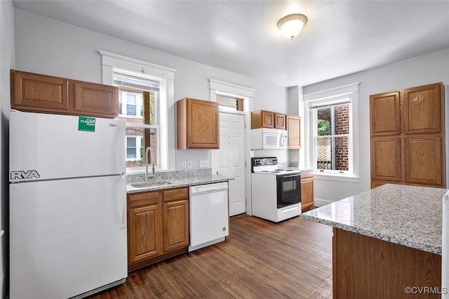 kitchen with white appliances, dark wood-type flooring, a sink, and a wealth of natural light