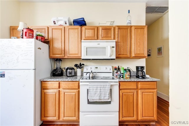 kitchen featuring white appliances, wood finished floors, visible vents, and baseboards