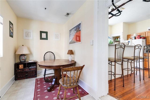 dining space featuring light wood-type flooring, visible vents, and baseboards