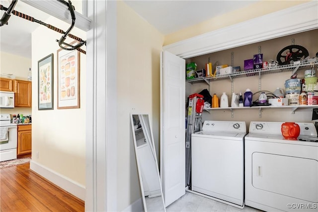 laundry area with washer and dryer, laundry area, light wood-style flooring, and baseboards