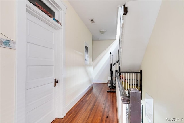 stairway featuring hardwood / wood-style floors, visible vents, and baseboards