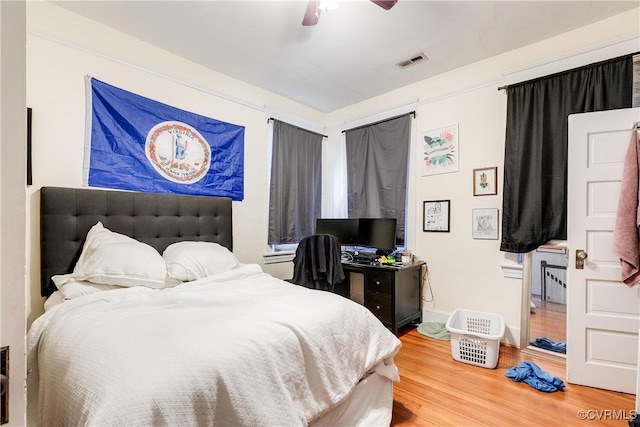 bedroom featuring a ceiling fan, visible vents, and wood finished floors