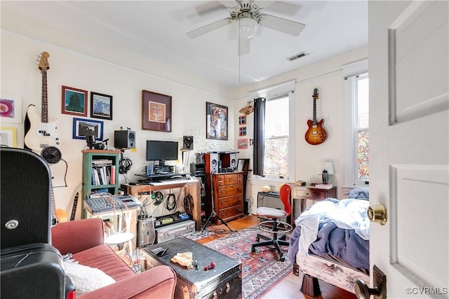 office featuring ceiling fan, light wood finished floors, and visible vents