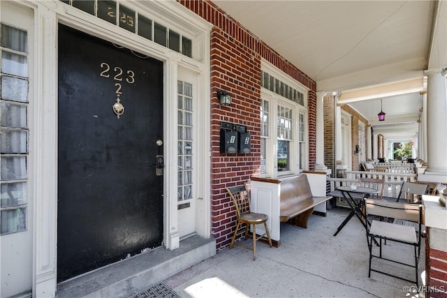 property entrance featuring a porch and brick siding