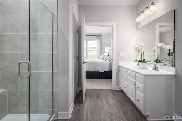 ensuite bathroom with connected bathroom, a sink, wood finished floors, a shower stall, and double vanity