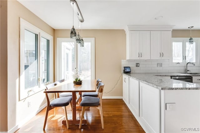 kitchen featuring white cabinets, light stone counters, backsplash, and a sink