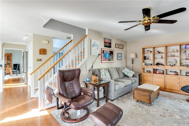 living area featuring stairs, a ceiling fan, and wood finished floors