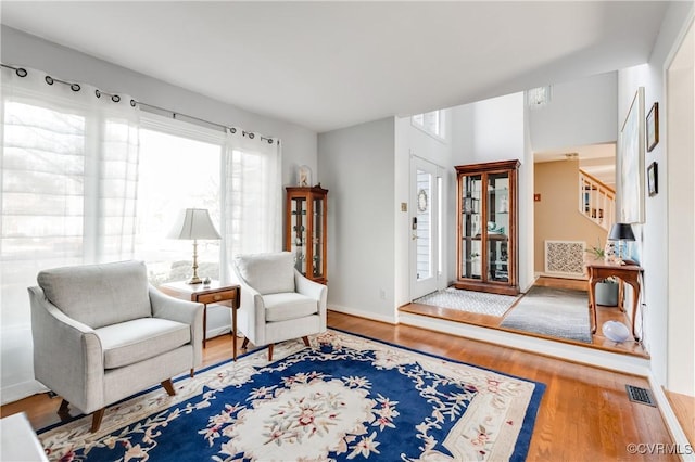 sitting room with stairway, wood finished floors, visible vents, and baseboards