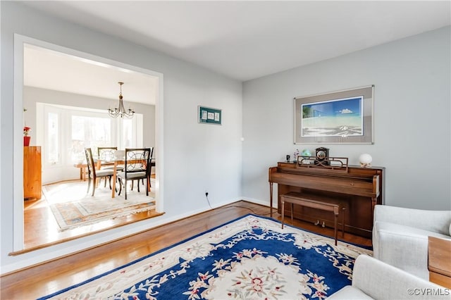 sitting room with baseboards, wood finished floors, and a chandelier