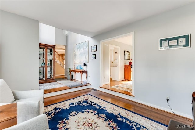 living room featuring stairs, wood finished floors, and baseboards