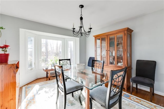 dining area with a notable chandelier, light wood-style floors, and baseboards