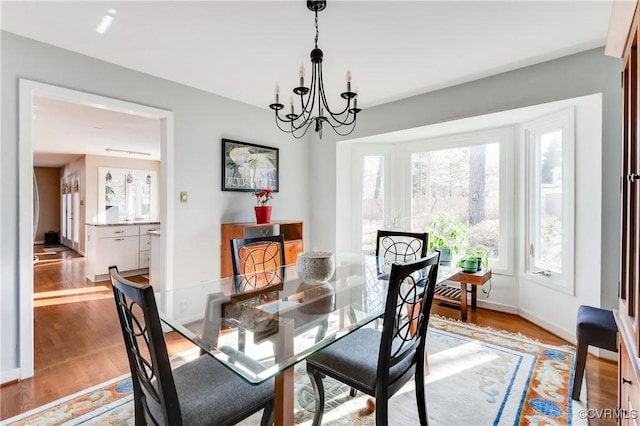 dining room featuring baseboards, an inviting chandelier, and light wood finished floors