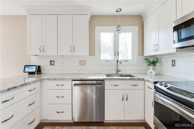 kitchen with a sink, white cabinets, backsplash, and stainless steel appliances