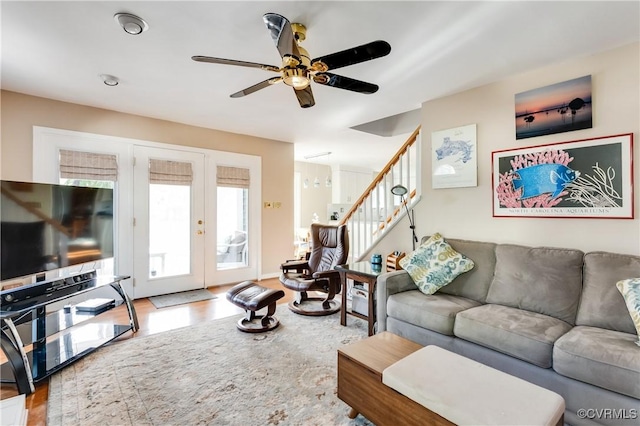 living area featuring stairway, wood finished floors, a ceiling fan, and french doors