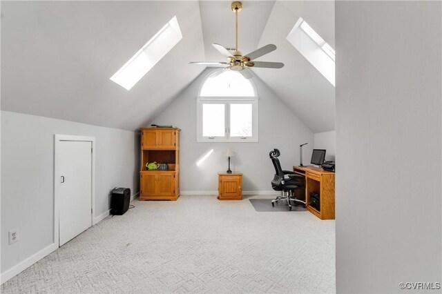 office space with light carpet, lofted ceiling with skylight, baseboards, and a ceiling fan