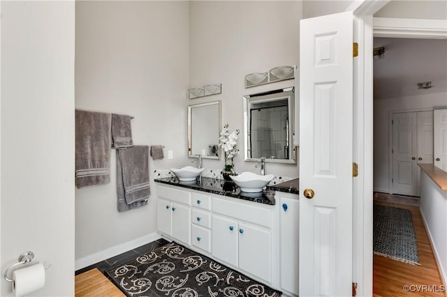 full bath with double vanity, baseboards, and a sink