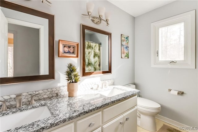 full bathroom featuring double vanity, toilet, baseboards, and a sink