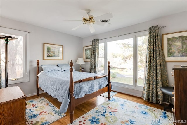 bedroom featuring visible vents, baseboards, ceiling fan, and wood finished floors