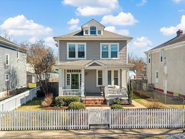 traditional style home featuring covered porch and a fenced front yard