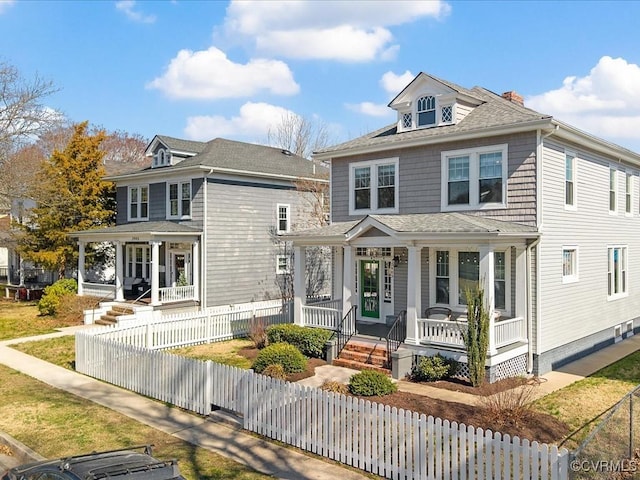 american foursquare style home with a fenced front yard, a porch, and roof with shingles