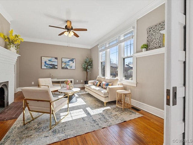 living area featuring hardwood / wood-style flooring, a brick fireplace, visible vents, and crown molding