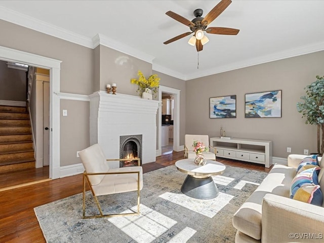 living room with a brick fireplace, stairway, baseboards, and wood finished floors