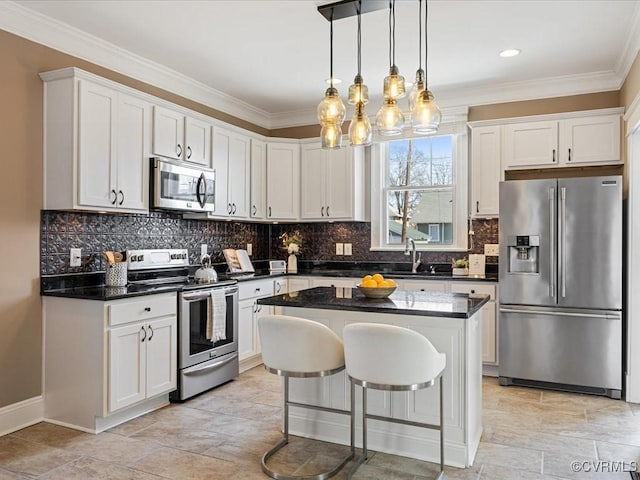 kitchen featuring stainless steel appliances, a kitchen island, a sink, white cabinets, and ornamental molding