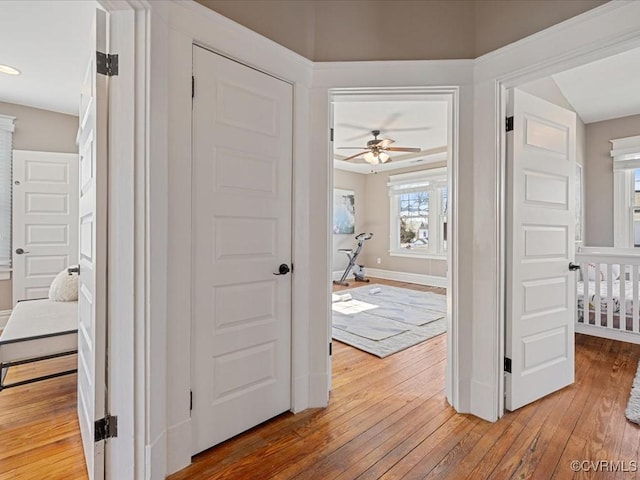 corridor featuring light wood-style floors and baseboards