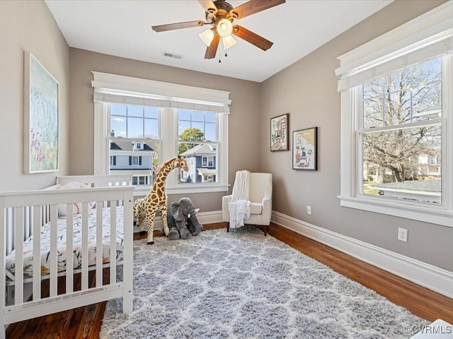 bedroom with a ceiling fan, wood finished floors, visible vents, and baseboards