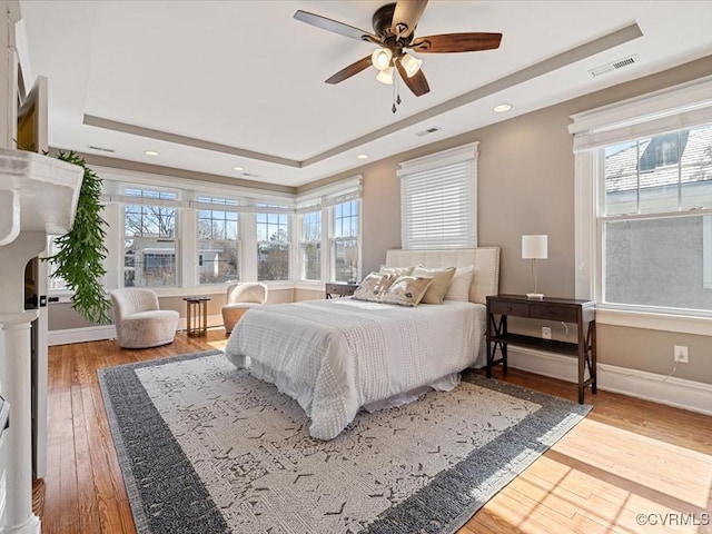 bedroom with a raised ceiling, visible vents, and hardwood / wood-style floors