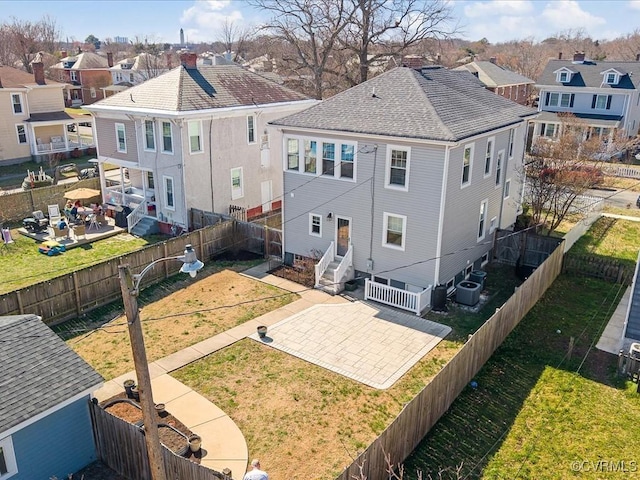 rear view of house featuring a residential view, a fenced backyard, a lawn, and entry steps