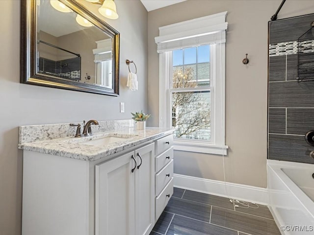 bathroom with washtub / shower combination, baseboards, and vanity