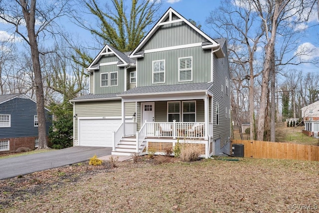 view of front of property with driveway, an attached garage, covered porch, fence, and central air condition unit