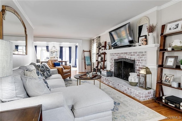 living area with ornamental molding, a brick fireplace, and wood finished floors