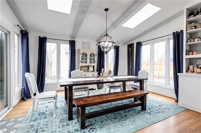 dining area featuring light wood-type flooring, lofted ceiling with skylight, plenty of natural light, and a notable chandelier