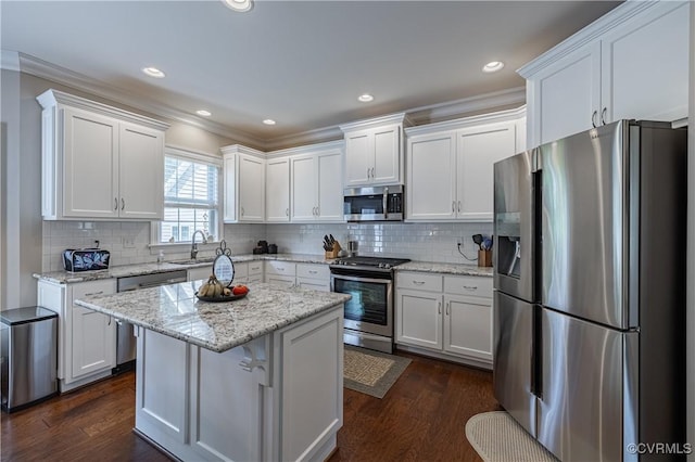 kitchen with appliances with stainless steel finishes, dark wood-type flooring, backsplash, and white cabinets